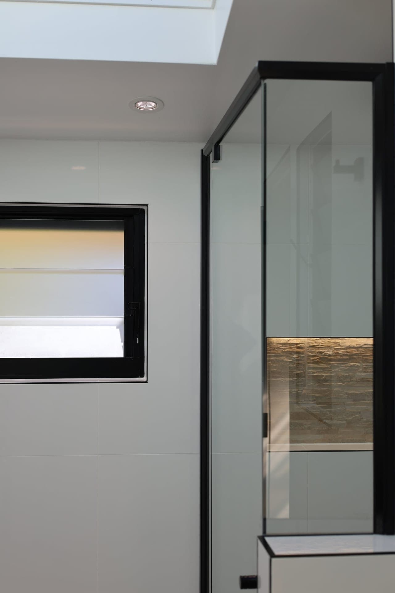 Frameless glass shower with a stone feature niche